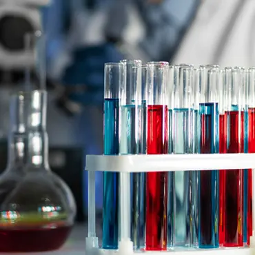 A scientist holds a test tube full of different colored liquids